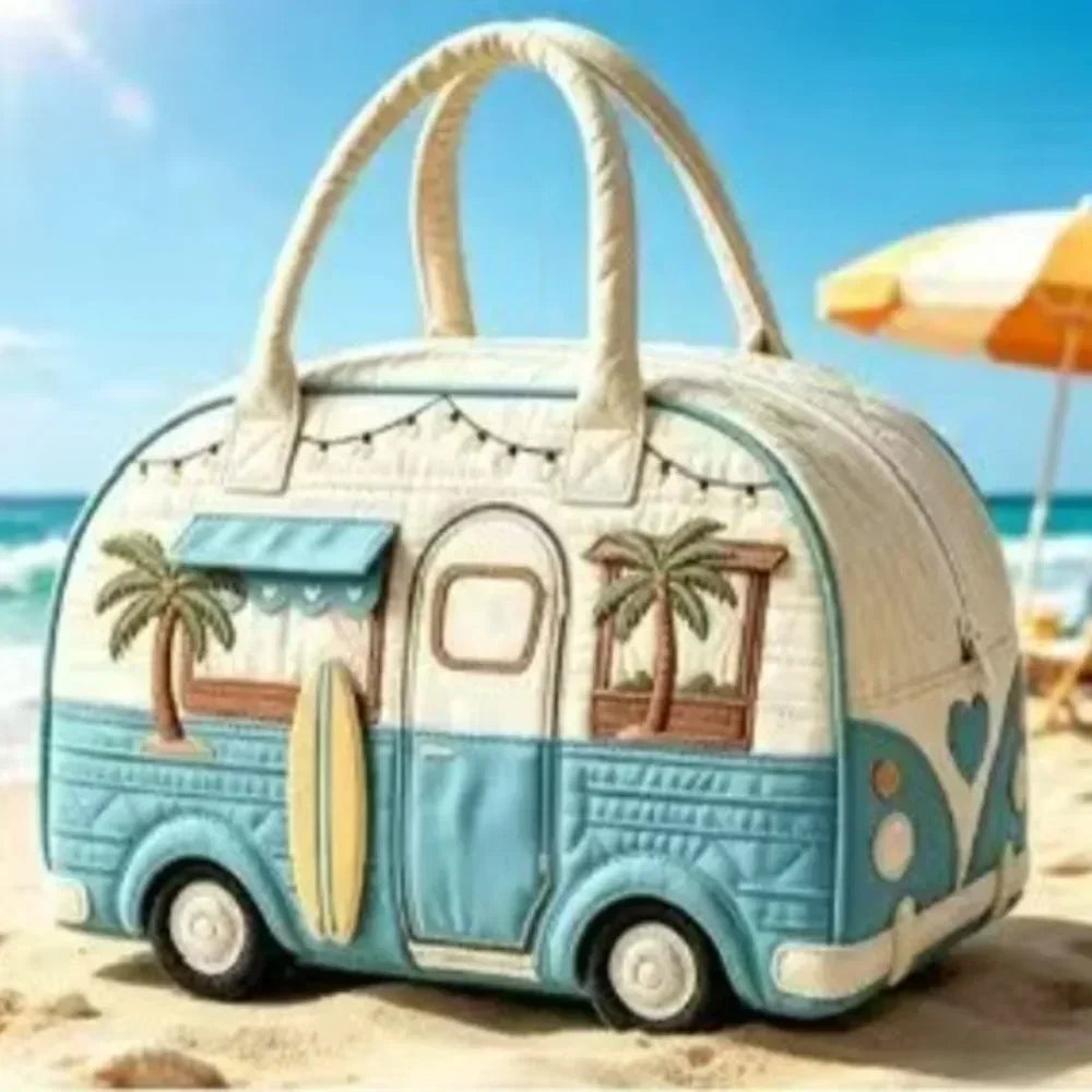 A light blue quilted travel duffle bag with a handle and palm tree design resting on a sandy beach.