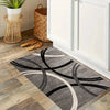 A minimalist geometric rug featuring black and white curved lines on a light wood floor.