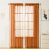 Two panels of sheer orange voile curtains hanging over a window.