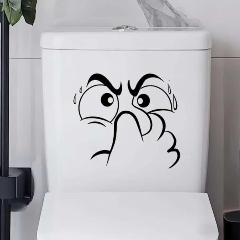 A white toilet lid features a black line drawing of an expressive, angry face.
