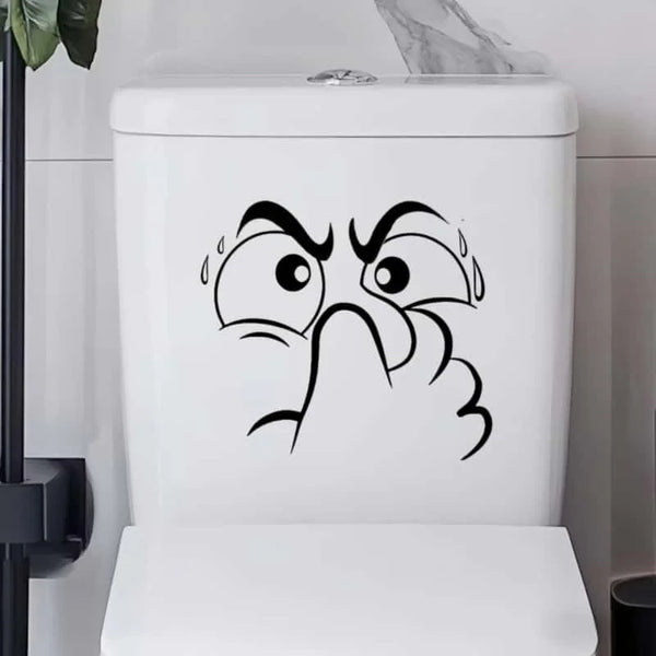 A white toilet lid features a black line drawing of an expressive, angry face.