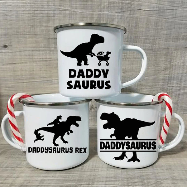 Dos tazas de café de cerámica blancas con siluetas negras de dinosaurios y texto como Daddy Saurus y Daddysaurus Rex