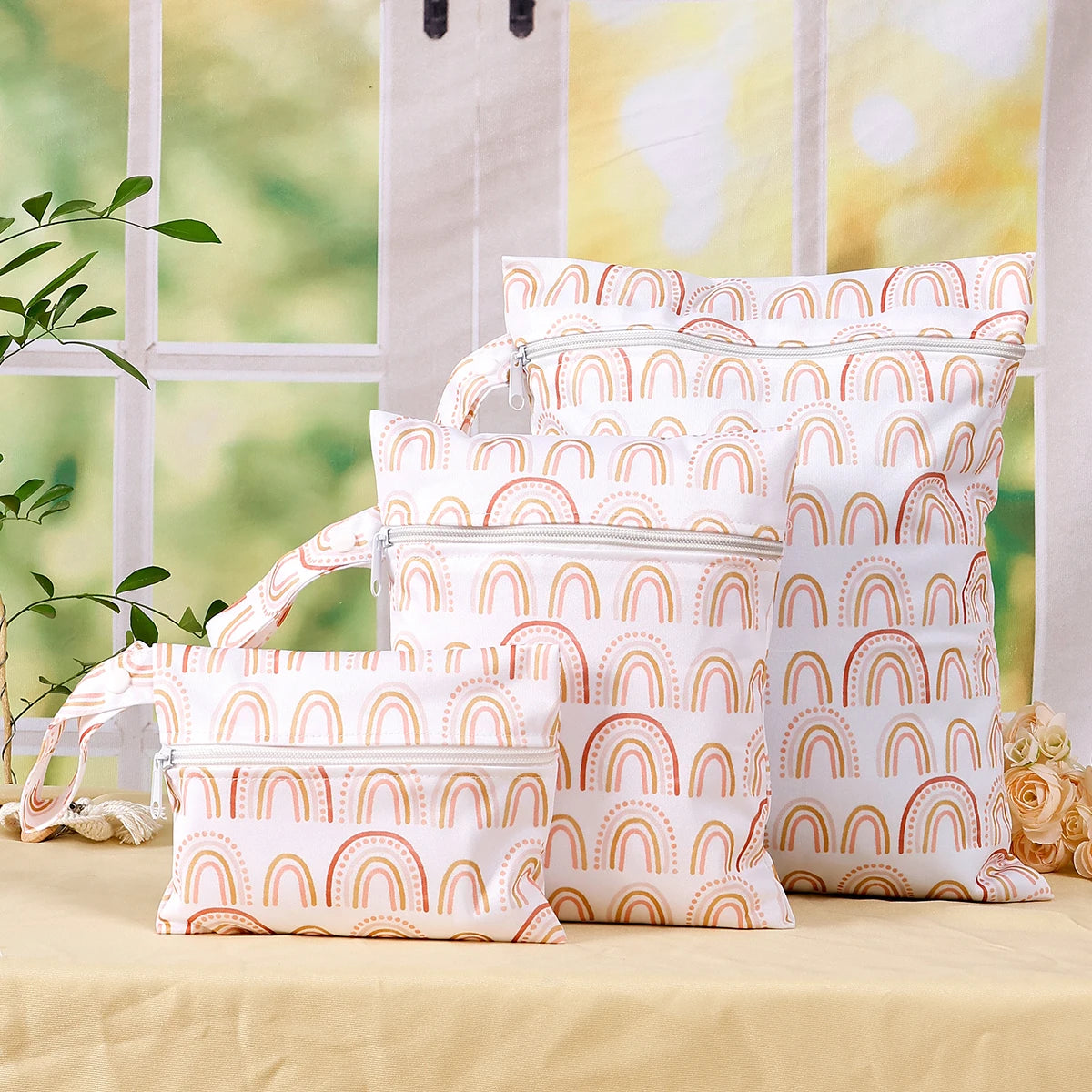 A set of reusable waterproof wet bags featuring a rainbow pattern displayed on a light beige surface.