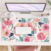 A pink floral desk pad featuring watercolor roses and greenery, placed under a computer monitor.