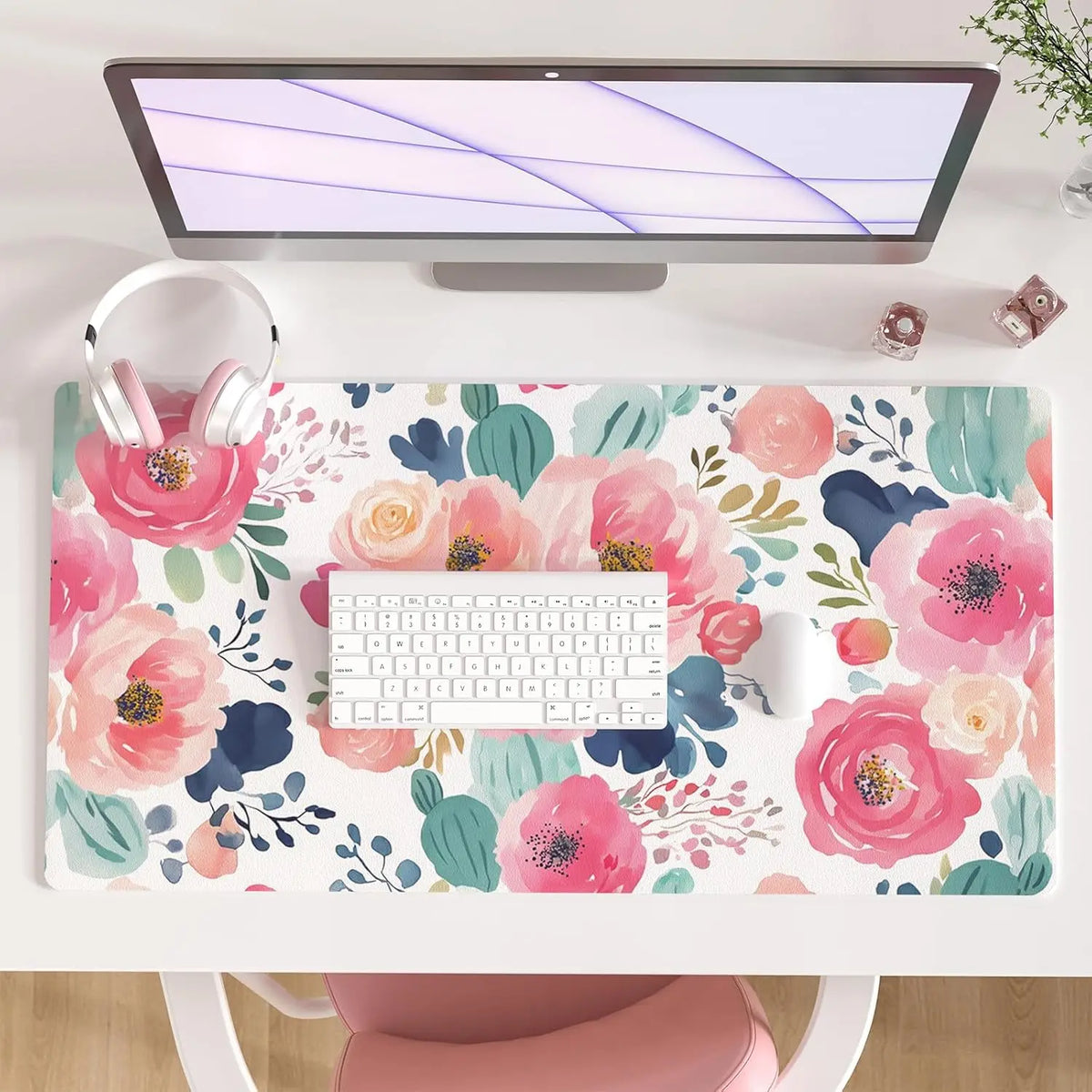 A pink floral desk pad featuring watercolor roses and greenery, placed under a computer monitor.