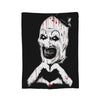 A black and white illustration of a clown face with blood splatters on a coral fleece throw blanket.