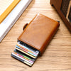 A brown leather wallet with a card slot is shown open, displaying several credit cards on a wooden surface.
