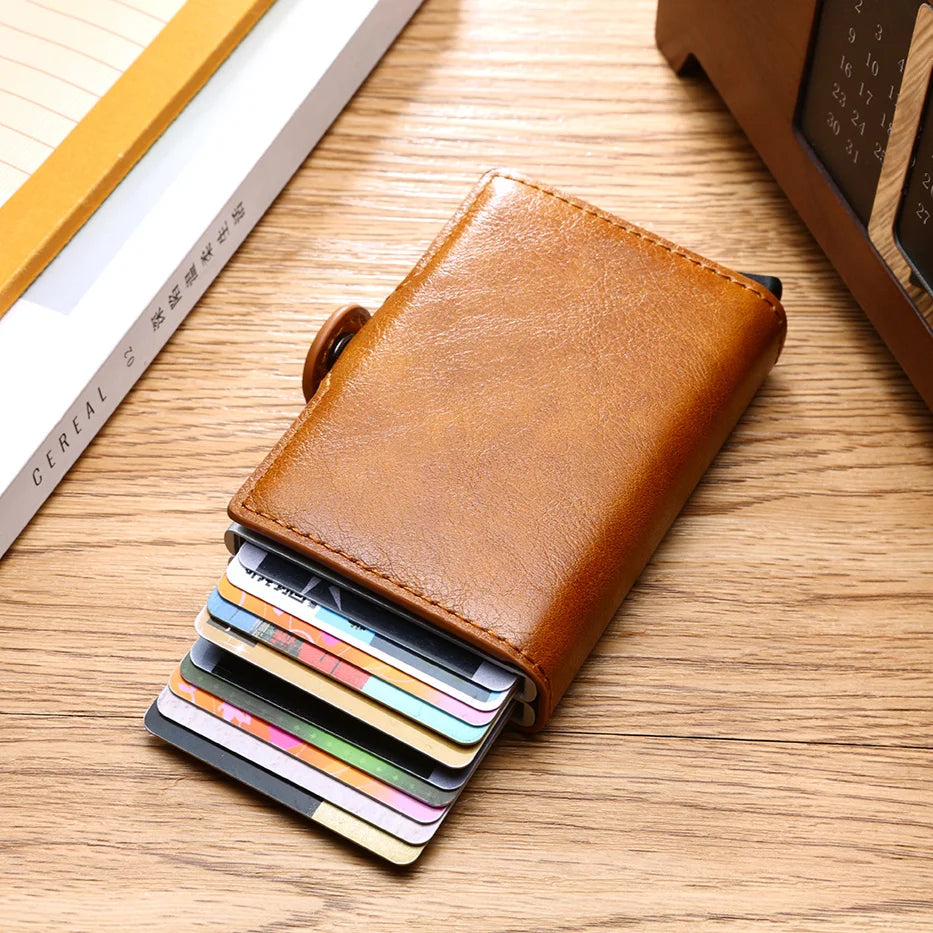 A brown leather wallet with a card slot is shown open, displaying several credit cards on a wooden surface.