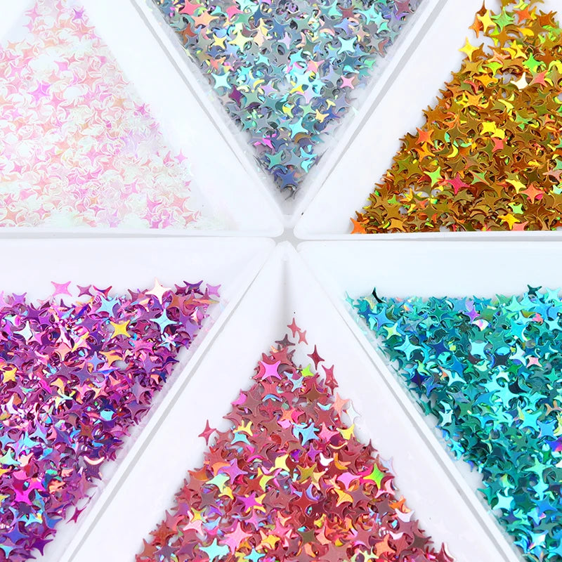 A collection of shiny holographic star sequins in various colors arranged in a square box.