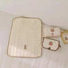 A beige quilted foldable portable diaper changing pad with several small fabric pouches.