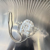 A clear acrylic chain shoulder bag adorned with round white sequins resting on a reflective surface.