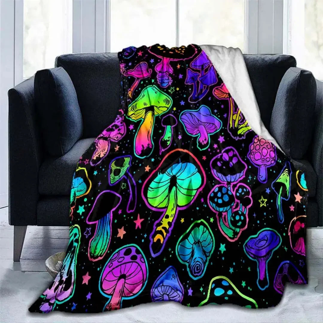 A colorful mushroom print flannel throw blanket draped over a dark sofa.