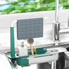 A silver adjustable over-sink dish drying rack with a teal handle and a blue plaid dishcloth is placed in a kitchen sink.