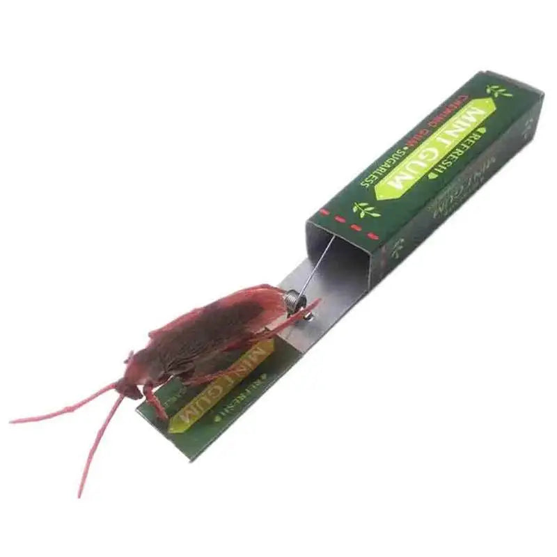 A realistic cockroach prank gum toy with a green wrapper and pink legs.