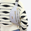 A person wearing a cream striped sweater is shown from the back, carrying a light gray nylon waist pack on their shoulder.
