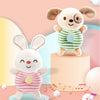 A soft plush baby rattle toy featuring a cartoon animal design, standing on a pink pedestal against a light background.