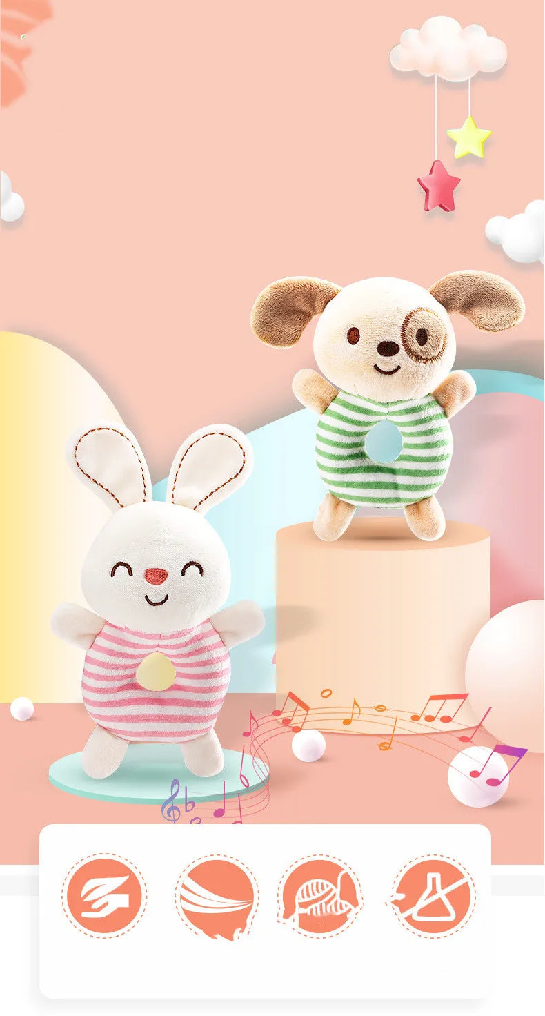 A soft plush baby rattle toy featuring a cartoon animal design, standing on a pink pedestal against a light background.