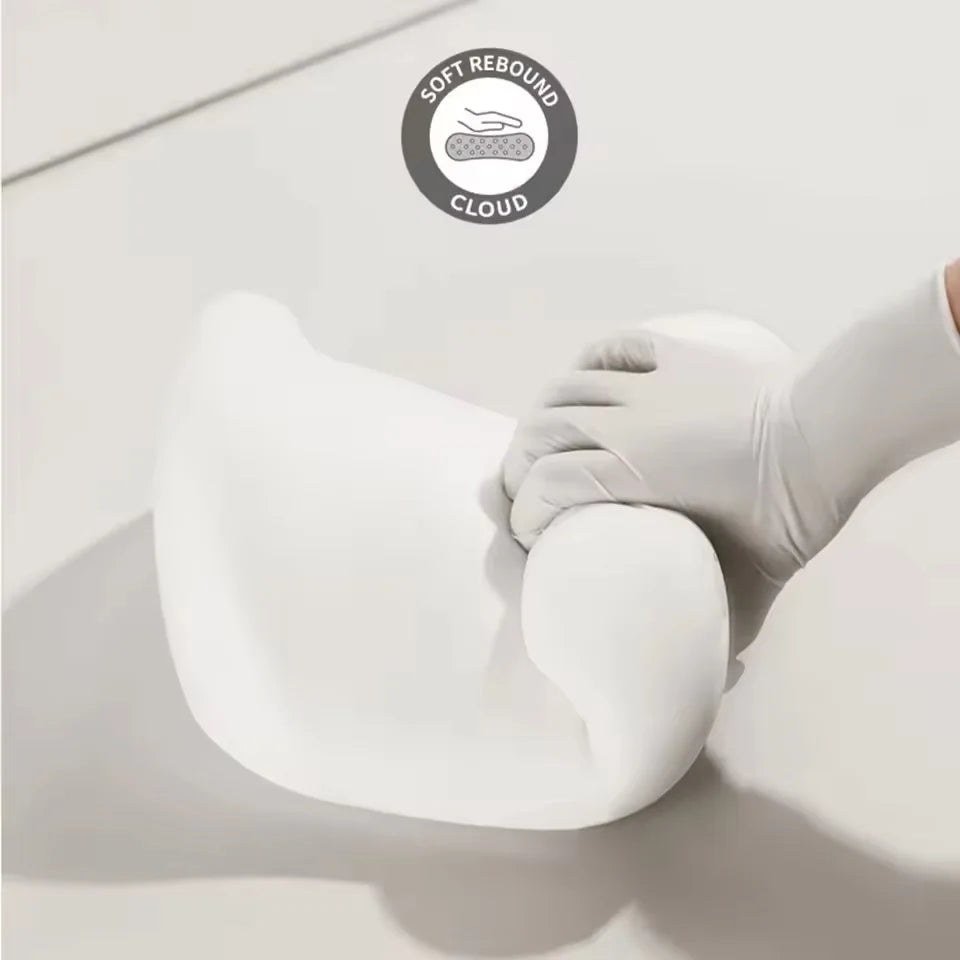 A white memory foam car headrest and lumbar support pillow being held by a hand, demonstrating soft rebound cloud technology.
