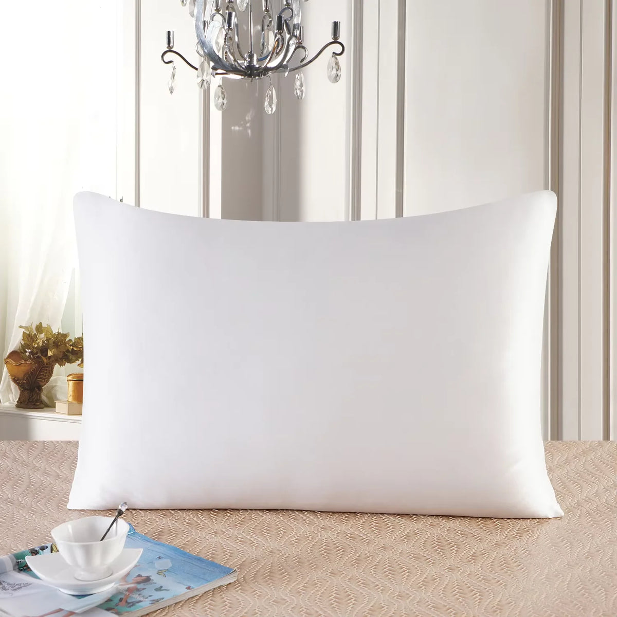 Housse de couette en soie de mûrier naturelle blanche posée sur une surface beige devant un mur lambrissé clair et un lustre.