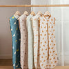 A display of five breathable cotton baby sleep sacks hanging on a wooden rack.