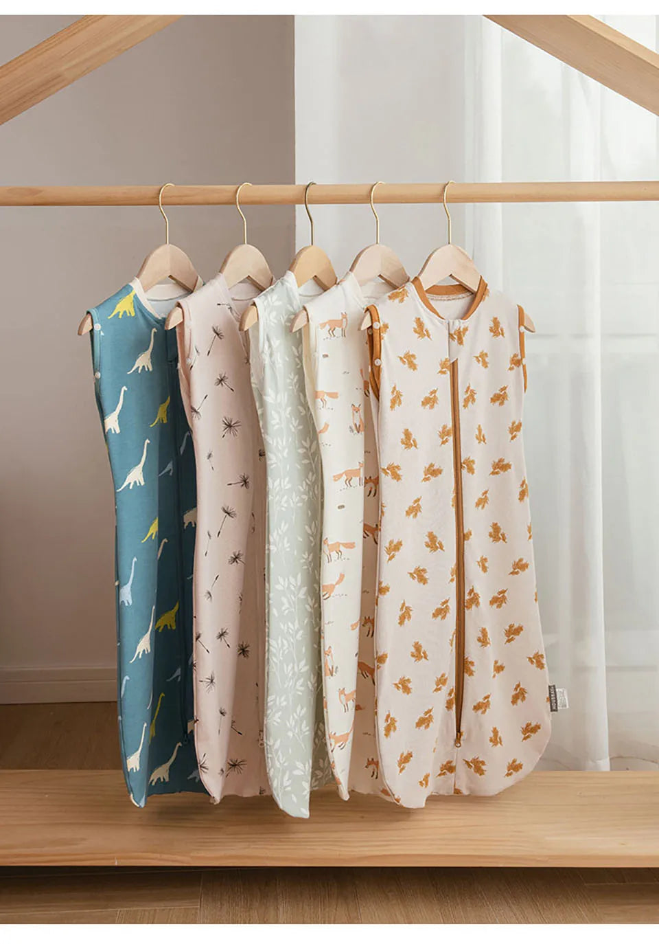 A display of five breathable cotton baby sleep sacks hanging on a wooden rack.
