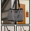 A black crystal-embellished chain shoulder bag hanging in front of a wooden door.