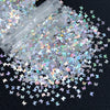 A close-up of shiny holographic star sequins scattered across a dark surface.