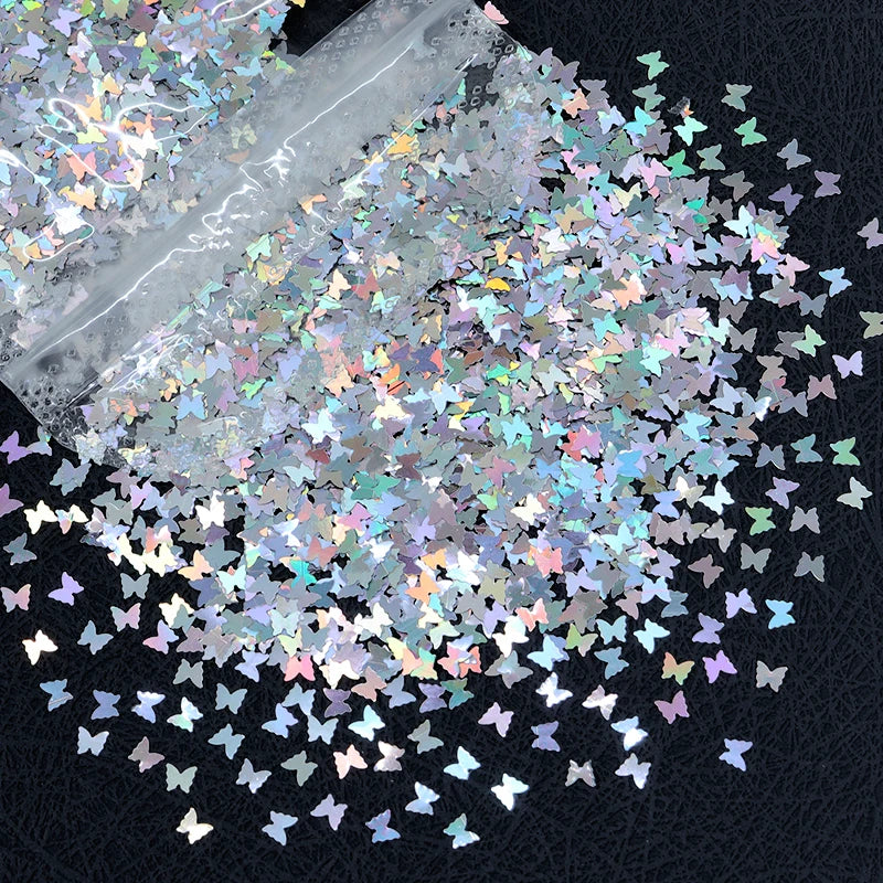 A close-up of shiny holographic star sequins scattered across a dark surface.