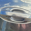 Close-up of a silver car door handle with black carbon fiber protective covers installed.
