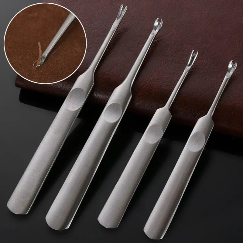 A set of four metal tools, including a groover and beveler, resting on a dark brown leather surface.
