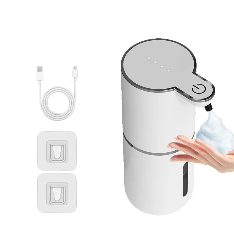 A white touchless automatic soap dispenser with a pump mechanism and a rechargeable battery cable shown next to the device.