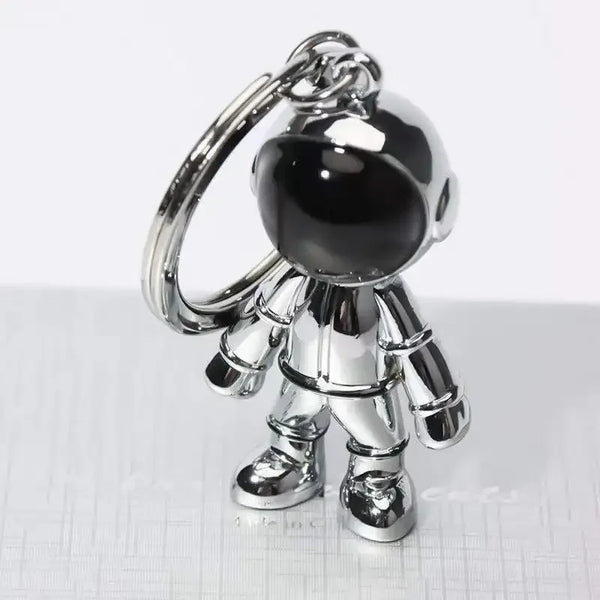 Colgante de llavero de astronauta plateado con una figura detallada y casco negro y traje.