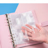 A hand holds an A5 budget binder with transparent inner pages and cash envelopes.