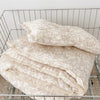 A stack of cream-colored floral muslin baby blankets folded in a wire basket.