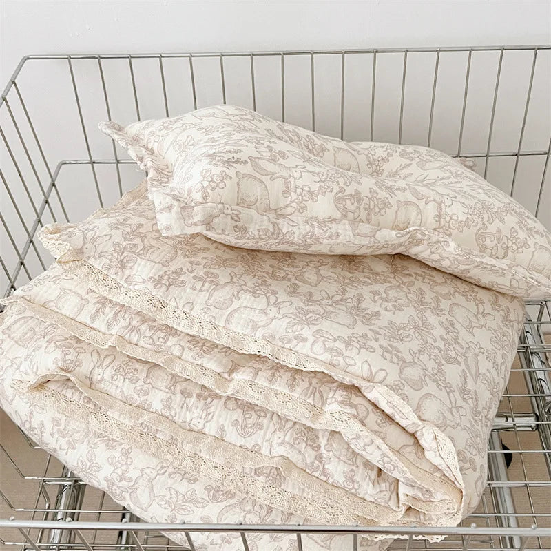 A stack of cream-colored floral muslin baby blankets folded in a wire basket.