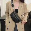 A woman wearing a beige blazer holds a black multi-pocket PU leather waist bag with an adjustable strap.