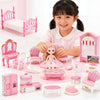 A young girl is surrounded by a pink dollhouse furniture set including beds, chairs, and accessories for creative play.