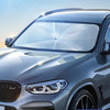 A silver SUV's front windshield is covered with a clear, foldable sunshade for UV protection.