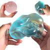 A hand holds a translucent blue squishy stress relief toy and a pink ball, showing its soft sensory nature.