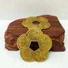 A set of traditional Chinese brass lucky coins for wealth and home decor resting on a dark wooden surface.