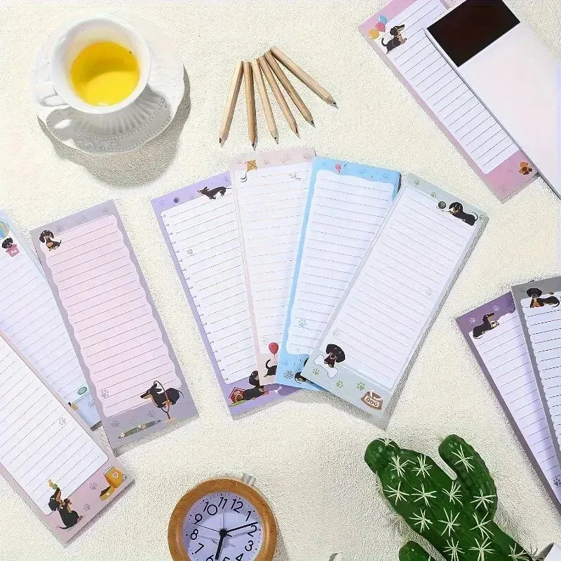 A collection of pink and blue magnetic dachshund themed to-do list notepads and wooden pencils on a light background.