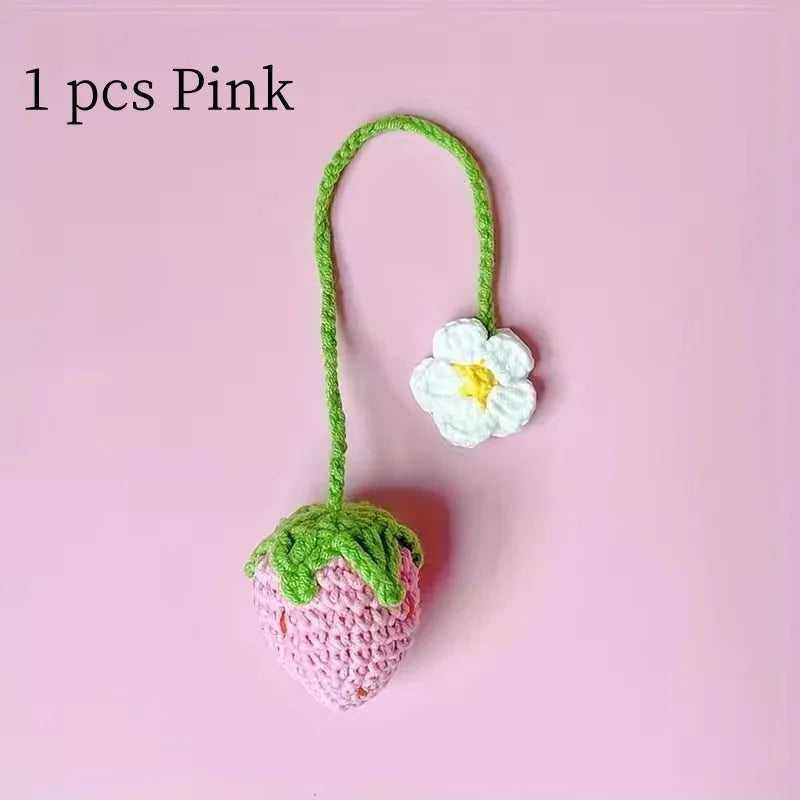 Handmade crochet pink strawberry pendant with a white flower detail on a green thread.