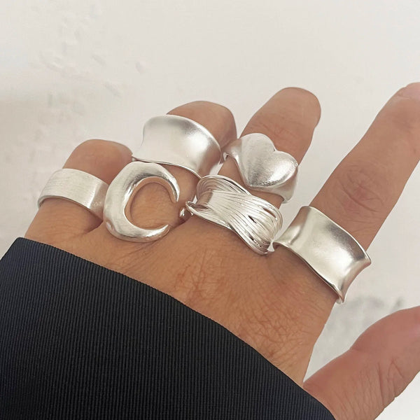 Una mano muestra un conjunto de anillos minimalistas de plata esterlina con forma de fases lunares en una muñeca.