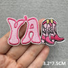 Pink embroidered iron-on patches shaped like the letters Y and A along with a pair of pink boots