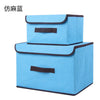 A set of two light blue fabric storage boxes with black trim for closet and drawer organization.