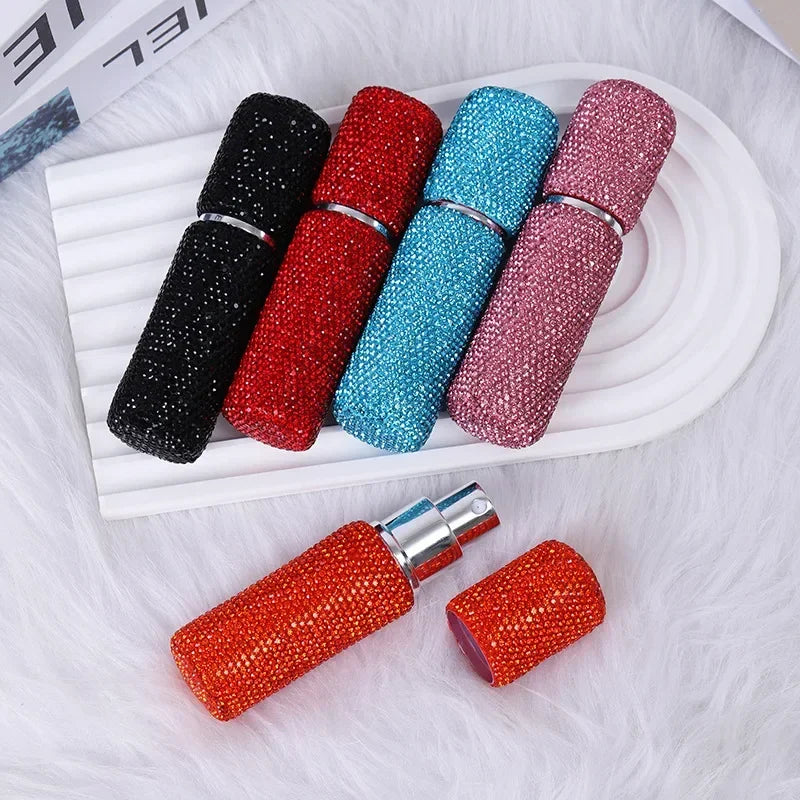 A collection of seven colorful refillable glass perfume atomizers in various shades including black, red, blue, and pink, dis