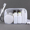 Clear PVC travel organizer bag holding various white and green toiletry bottles and a toothbrush.