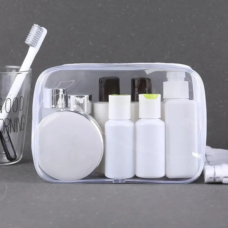 Clear PVC travel organizer bag holding various white and green toiletry bottles and a toothbrush.