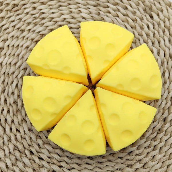 Yellow cheese squishy stress toy shaped like wedges resting on a woven mat.