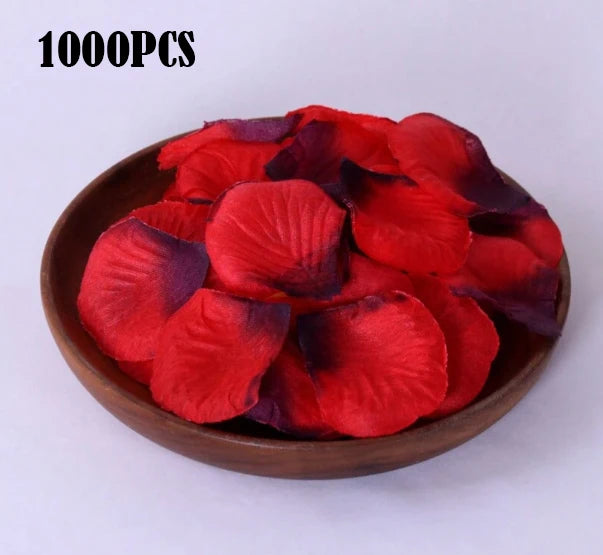 A pile of 1000 pieces of deep red and purple silk rose petals in a wooden bowl.